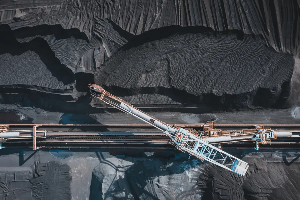Top view of modern industrial machinery working with black natural coal in daylight